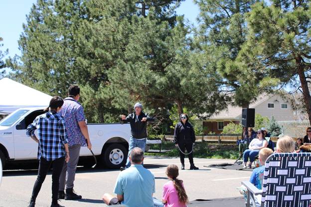 Actors in a parking lot with an audience watching. 