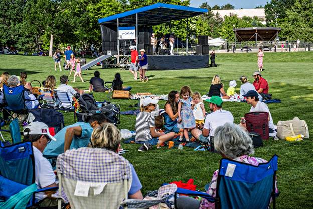 An audience is listening to music on a stage in a park.